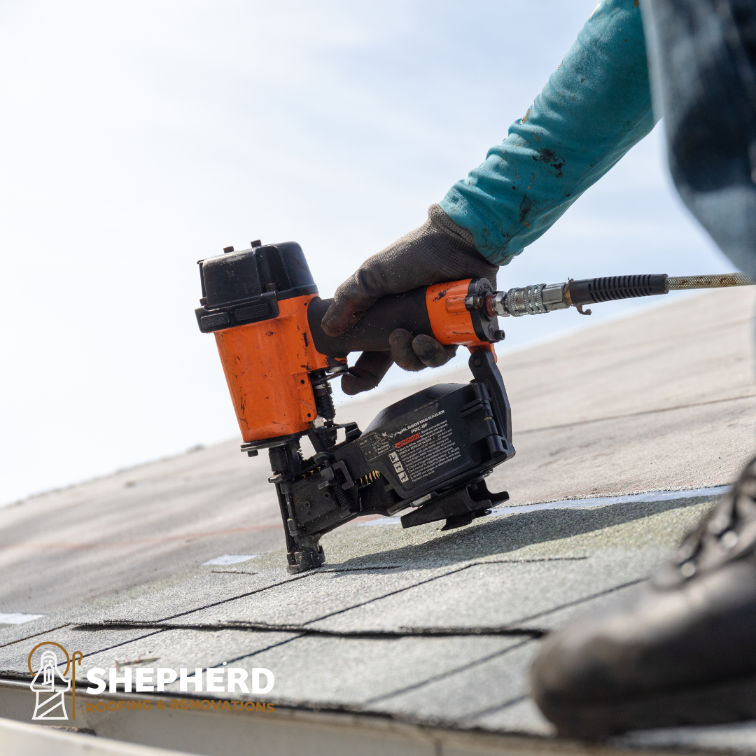 worker nailing roof shingles on roof